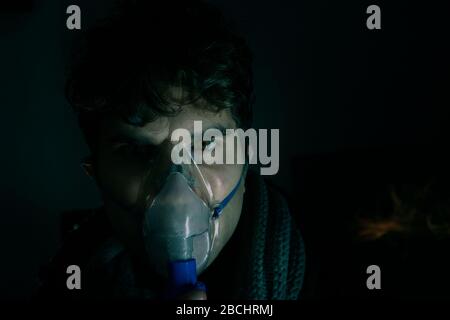 Dark Portrait of man Using Steam Vapor Inhaler nebulizzatore fare aerosol inalazione medicina trattamento a casa o ospedale influenza e asma bronchite vir Foto Stock