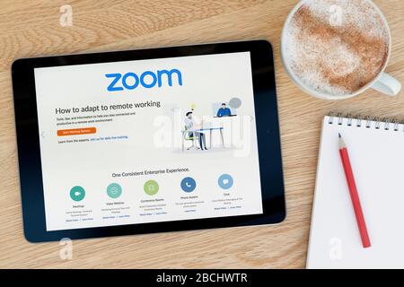 Il sito Web per videoconferenze Zoom è disponibile su un tablet iPad che si appoggia su un tavolo in legno accanto a un blocco note (solo per uso editoriale). Foto Stock