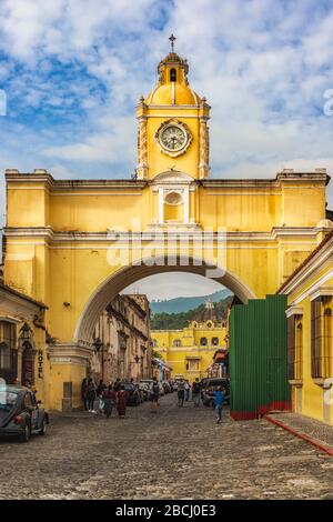 Antigua, Guatemala – 5 dicembre 2020: Persone che camminano sulla strada principale e sotto l'arco giallo di Santa Catalina nel centro storico di Antigua, Guate Foto Stock