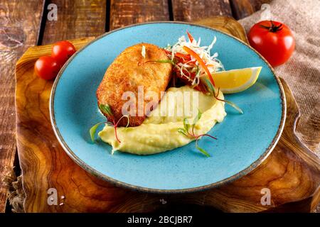 cotoletta di carne servita con purè di patate e verdure kortofel sullo sfondo di un tavolo di legno Foto Stock