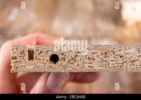 Truciolare con scanalatura fresata. Foro nel pannello di mobili. Sfondo chiaro. Foto Stock