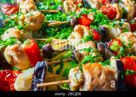 Fettine di pollo, melanzane, pomodoro, peperoni dolci e funghi sono strung su spiedini di legno e fritti fino a rosato. Deliziosa prelibatezza con fresco ch Foto Stock