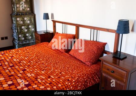 Antica camera da letto vintage retro con letto in camera con decorazioni vecchio stile e camino in casa in Europa Foto Stock