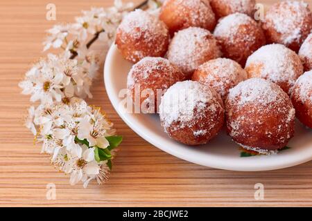 Buchi di ciambella fatti in casa con un brach fiorente sulla scrivania, durante l'isolamento pandemico Foto Stock
