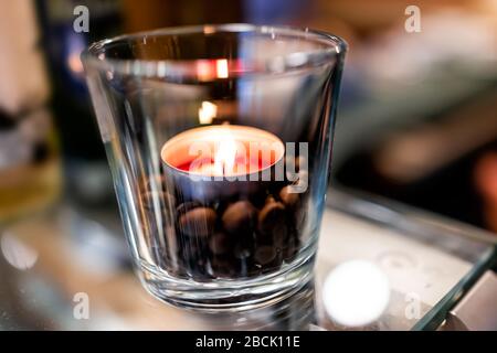 Macro closeup di piccolo tè rosso candela su tavolo di vetro in tazza caffè ristorante atmosfera romantica sfondo sfocato e caffè in grani arrosto Foto Stock