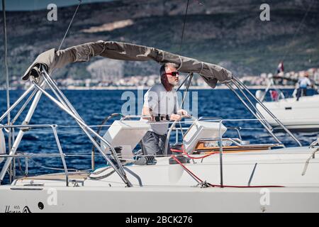 Croazia, Mare Adriatico, 18 settembre 2019: Il brutale capitano della barca è al volante, barche a vela competere in una regata di vela, corsa in barca a vela Foto Stock