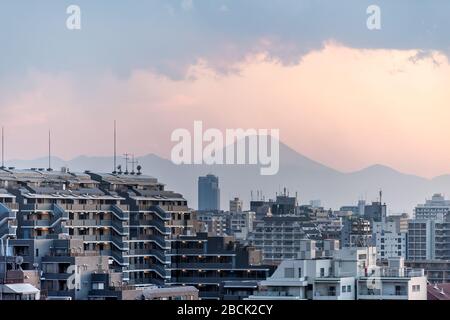 Tramonto rosa a Tokyo, Giappone Shinjuku paesaggio urbano con silhouette vista del Monte Fuji e luce solare dorata, edifici di appartamenti e montagne con la pioggia clo Foto Stock