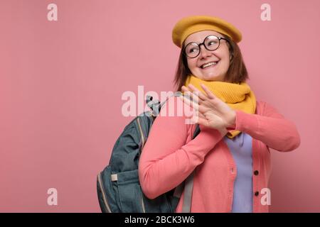 Giovane donna caucasica che agita mano dicendo addio ai suoi amici in piedi isolato su sfondo rosa guardando macchina fotografica sorridente giocoso Foto Stock