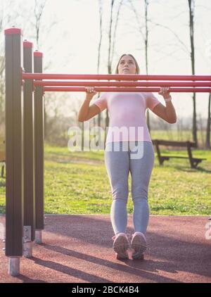 Giovane donna che fa australiano tirare UPS nel parco Foto Stock