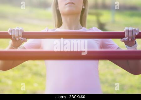 Giovane donna che fa australiano tirare UPS nel parco Closeup Foto Stock