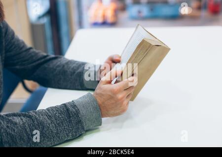 Giovane uomo che legge il vecchio libro di carta aperto al tavolo, primo piano, stile vintage Foto Stock