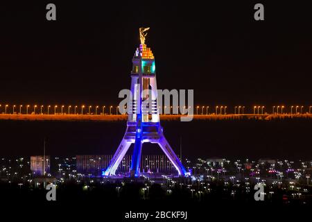 Monumento alla neutralità di notte ad Ashgabat, Turkmenistan costruito con marmo bianco. Statua d'oro di Saparmurat Niyazov in cima. Arco di neutralità. Foto Stock