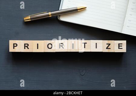 Parola d'ordine per gli affari moderni - priorità. Vista dall'alto su tavolo in legno con blocchi. Vista dall'alto. Primo piano. Foto Stock