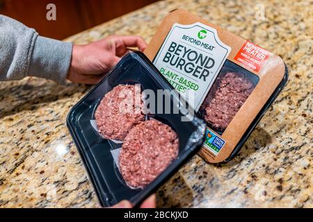 Herndon, Stati Uniti - 3 febbraio 2020: Persona dell'uomo che tiene uncooked oltre i pacchetti del hamburger delle pattuglie di pianta-basate con gli hamburger sopra il countertop della cucina Foto Stock