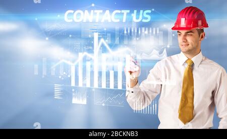 Bel uomo d'affari con casco disegno CONTATTACI iscrizione, architettura business plan concept Foto Stock