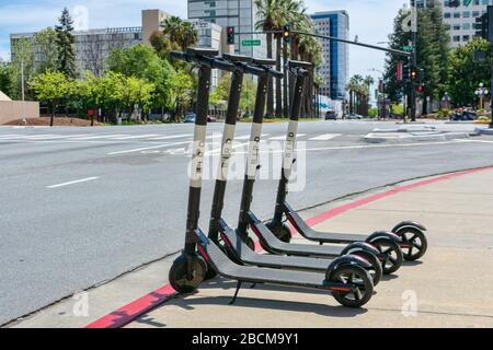 Sparatutto elettrici per uccelli rideshare sul marciapiede nel centro della città durante il giorno di sole. Bird è un affidabile ultimo miglio di noleggio scooter elettrico senza molo - SA Foto Stock