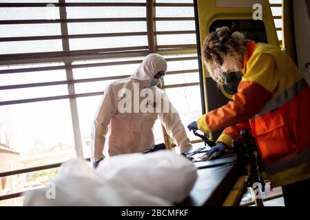 Gli operatori sanitari di emergenza in dispositivi di protezione come misura preventiva, finalizzando un trasferimento di un possibile caso di covid-19. I servizi sanitari di emergenza sono costretti a rispettare protocolli specifici durante i trasferimenti di pazienti con possibili casi di covid-19. Al termine del servizio, disinfettano e gettano i dispositivi di protezione individuale in sacchetti G-II per evitare il rischio di contagocci. Foto Stock