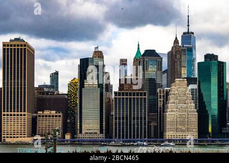Vista scura degli edifici sul lungomare di New York City dall'altra parte dell'East River in una giornata nuvolosa Foto Stock