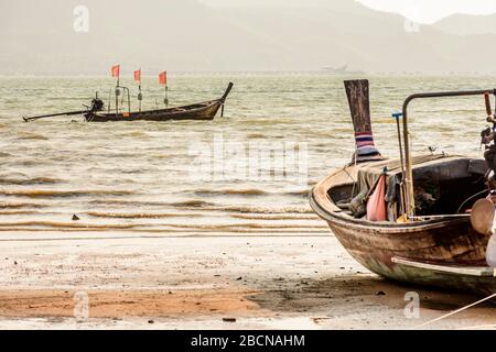 Barche a coda lunga e ancorate durante il tardo pomeriggio ventoso, bassa marea sull'isola di Ko Yao noi a Phang-Nga Bay vicino a Phuket, Thailandia Foto Stock