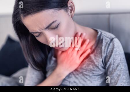 I sintomi del virus Corona COVID-19 sono polmonite, respiro corto, febbre, dolori del corpo o difficoltà respiratorie. Donna asiatica malata di Coronavirus con area rossa che mostra dolore. Foto Stock