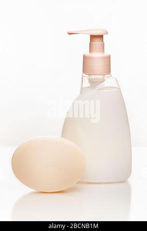 sapone e una bottiglia con sapone o shampoo crema, rosa su sfondo bianco. foto verticale ravvicinata. Foto Stock