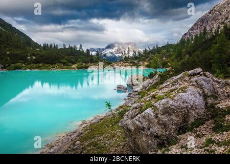 Paesaggio alpino estivo. Famosa località escursionistica, fotografia e ricreazione. Lago di Sorapis con alte montagne innevate in giornata nuvolosa, Dolomiti, Foto Stock