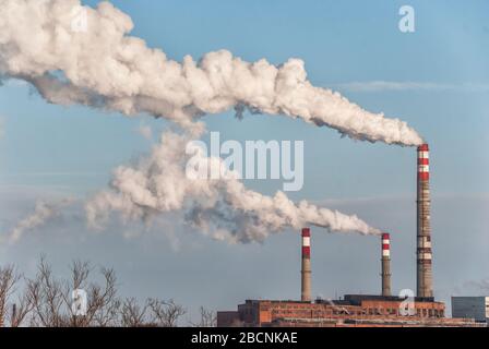 Vecchi camini di fabbrica con fumo bianco contro un cielo blu Foto Stock