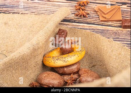 Bagel, torte al cioccolato, biscotti, anice stellato e cioccolato su uno sfondo di tessuto omespun grossolano. Primo piano Foto Stock