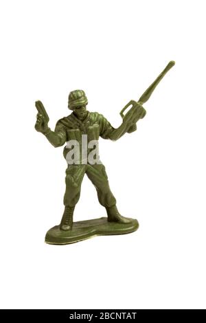 Semplice soldato giocattolo verde scuro in plastica che tiene una pistola e una mitragliatrice in mano che li tiene in su in un gesto di vittoria figura fanteria oggetto isolato Foto Stock