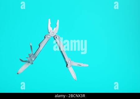 Lo strumento multifunzione multitool si trova su uno sfondo blu. Il concetto di un multi-utensile espanso con spazio libero. Foto Stock