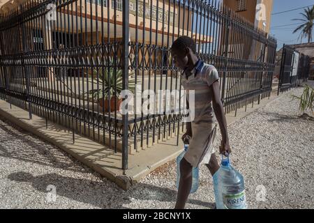 Boy sta trasportando l'acqua potabile a casa a Joal-Fadiouth in Senegal Foto Stock