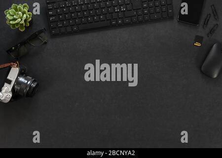 Vista dall'alto della scrivania da ufficio in cemento nero con computer, fotocamera e accessori Foto Stock