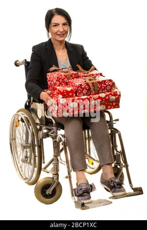Donna sicura seduta in sedia a rotelle e in possesso di regali di Natale isolato su sfondo bianco Foto Stock