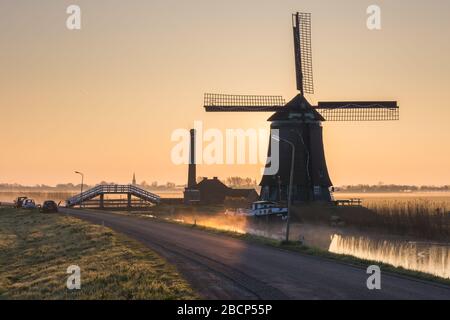 Il mulino a vento De Kaagmolen di fronte a un canale e barca, Olanda del Nord, Paesi Bassi Foto Stock