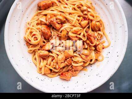 Tagliatelle di udon cinesi con pollo e funghi con salsa dolce e acea in una ciotola di wok asiatico Foto Stock