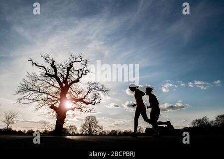 Due corridori mantengono la forma (sotto blocco per Corona virus Covid 19 restrizioni) su Clapham Common nel marzo 2020 Foto Stock