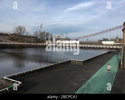 Glasgow, Scozia, Regno Unito. 5th Apr, 2020. La gente esercita lungo il lato del fiume Clyde. Strade vuote nell'estremità orientale del centro della città, che illustrano che le linee guida di distanziamento sociale e gli avvisi 'Say at home' sono stati rispettati nel periodo di Coronavirus COVID-19 pandemic Crisis. Foto di credito: jeremy sutton-hibbert/Alamy Live News Foto Stock