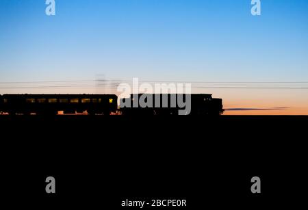 Servizi ferroviari diretti classe 37 locomotiva 37059 creare una silhouette al tramonto sulla costa occidentale linea principale al tramonto con un treno di prova ferroviario Network Foto Stock