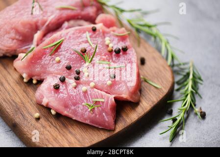 Carne di maiale cruda su tagliere di legno sul tavolo da cucina per cucinare bistecca di maiale arrosto o grigliato con ingredienti erbe e spezie, maiale fresco Foto Stock