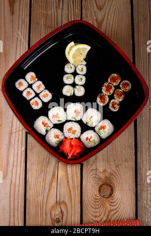 grande set di sushi colorato in un piatto quadrato. su uno sfondo di legno Foto Stock