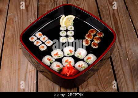 grande set di sushi colorato in un piatto quadrato. su uno sfondo di legno Foto Stock