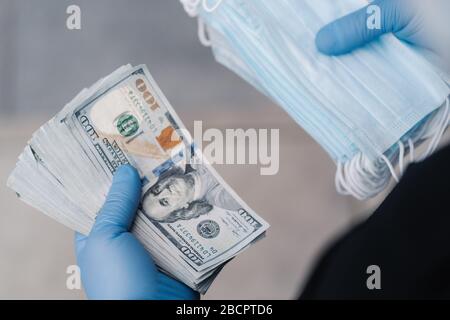 L'uomo irriconoscibile ha guadagnato molto soldi dopo la vendita delle maschere mediche, indossa i guanti protettivi. Focolaio di coronavirus e prevenzione. Mancanza di maschere facciali Foto Stock