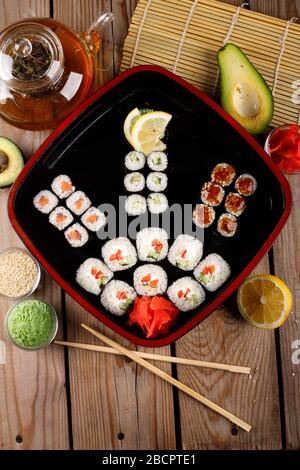 grande set di sushi colorato in un piatto quadrato. su uno sfondo di legno Foto Stock