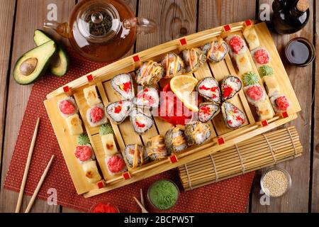 grande set di sushi colorato in un piatto quadrato. su uno sfondo di legno Foto Stock