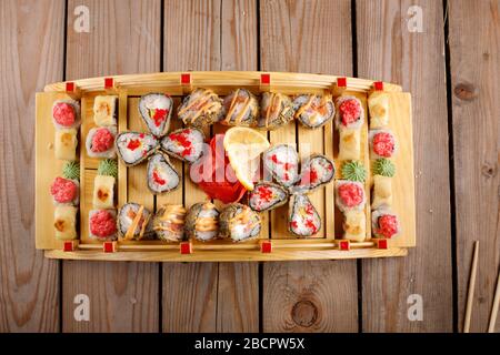grande set di sushi colorato in un piatto quadrato. su uno sfondo di legno Foto Stock