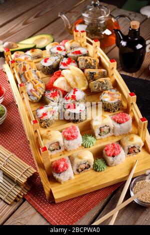 grande set di sushi colorato in un piatto quadrato. su uno sfondo di legno Foto Stock
