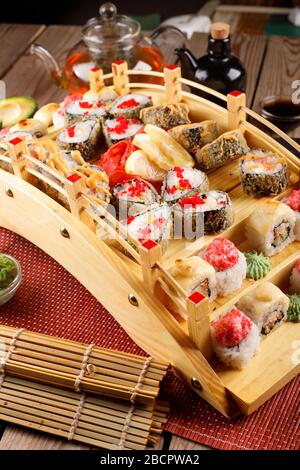 grande set di sushi colorato in un piatto quadrato. su uno sfondo di legno Foto Stock