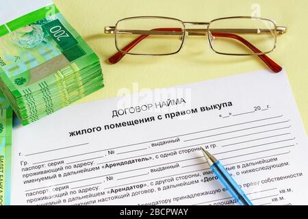Una forma, penna, bicchieri e rubli russi sul tavolo. L'iscrizione in russo 'Contratto di locazione di locali residenziali con il diritto di acquistare. Th Foto Stock