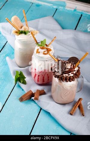 Caramello e cioccolato coccolanti milkshake estremi con torta al cioccolato, biscotti, marshmallows e caramelle. Tendenza pazzesca a mikshake cibo. Foto Stock