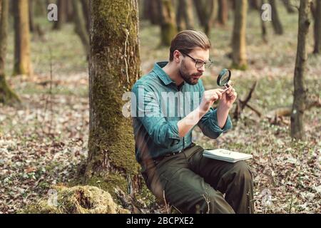 Botanico che studia muschio attraverso magniglass Foto Stock